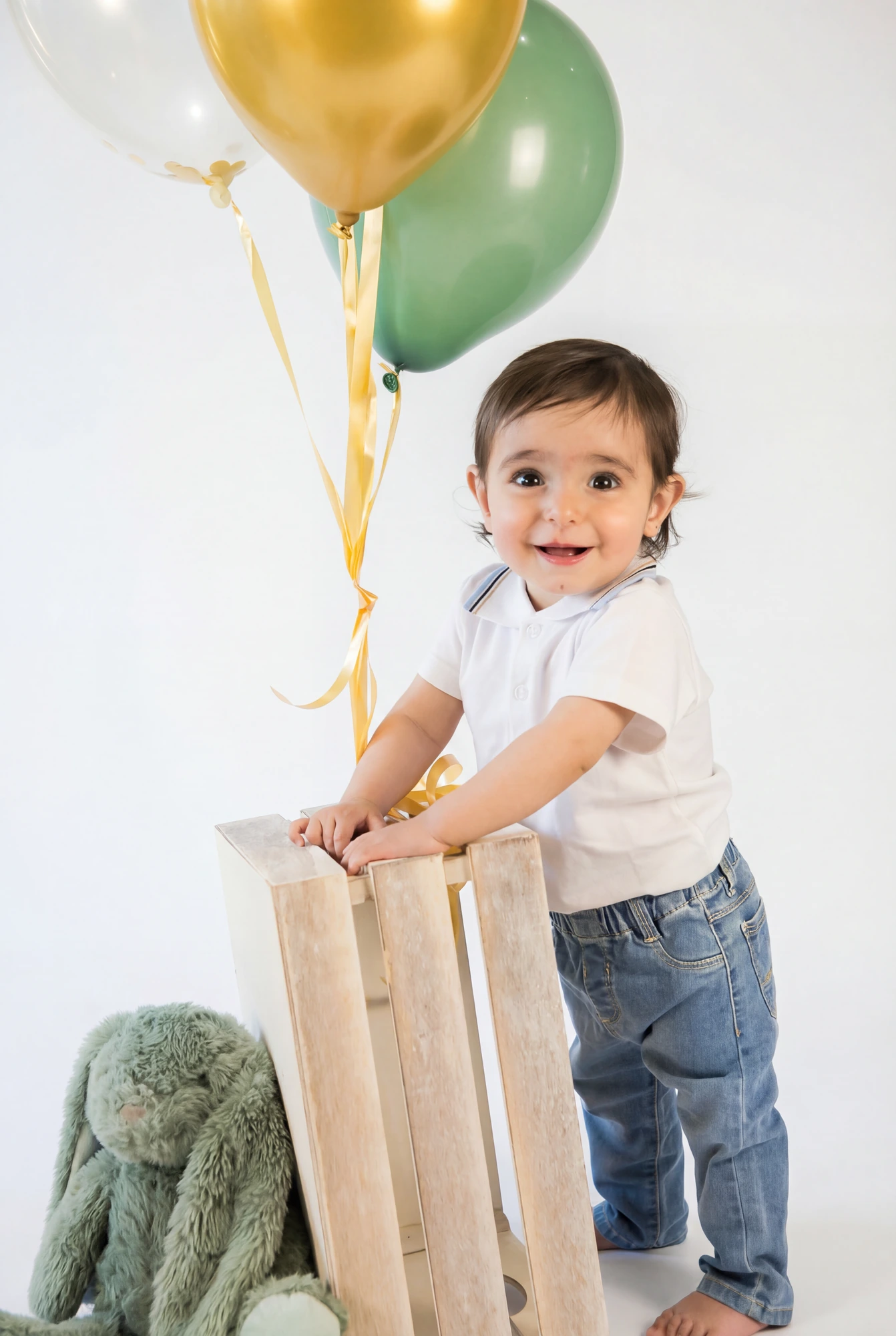 Niño junto a globos verdes y dorados