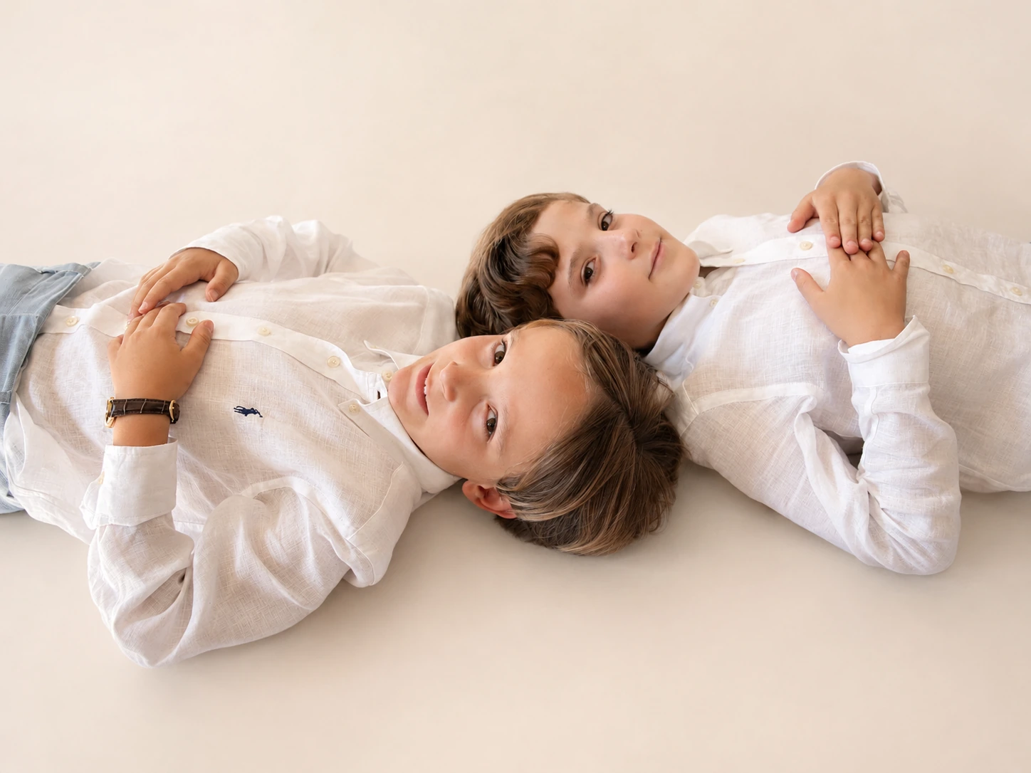 Dos niños tumbados juntos sobre un fondo claro